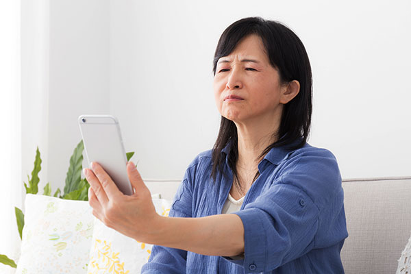 Woman struggling to read text message due to presbyopia