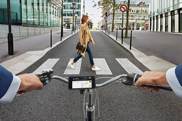 Man cycling on road and woman crossing on zebra crossing