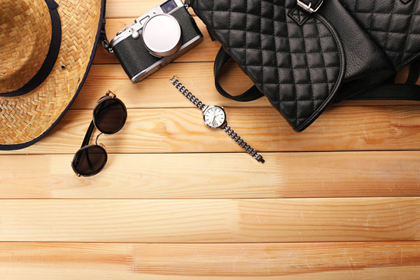 Layout of sunglasses, sunhat, camera, watch and handbag