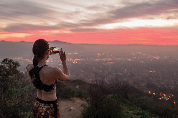 Woman in jogging attire taking picture of a sunset