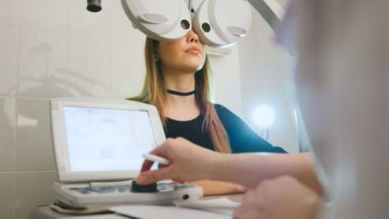 A woman having a full eye examination with an phoropter head