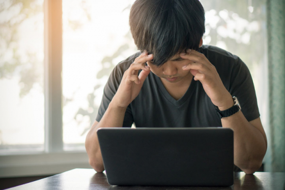 Man working from laptop experiences a migraine
